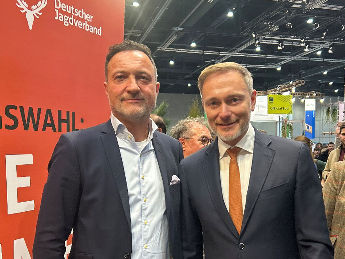 FDP-Chef Christian Lindner (rechts) und Matthias Klotz, Vorsitzender des Bundesverbands zivile Legalwaffen e. V. (BZL), stehen auf einer Messe vor einem Stand des Deutschen Jagdverbands und posieren für ein Foto.