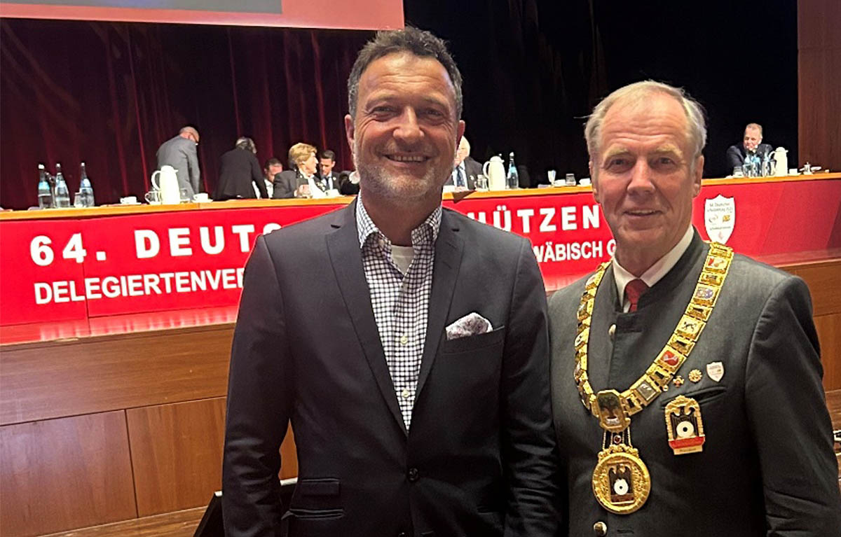 Matthias Klotz, Vorsitzender des Bundesverbands zivile Legalwaffen e. V. (BZL), gemeinsam mit Hans-Heinrich von Schönfels, altem und neuem Präsidenten des Deutschen Schützenbundes (DSB), bei einer Veranstaltung; im Hintergrund ein Sitzungssaal mit Banner des Schützenwesens.