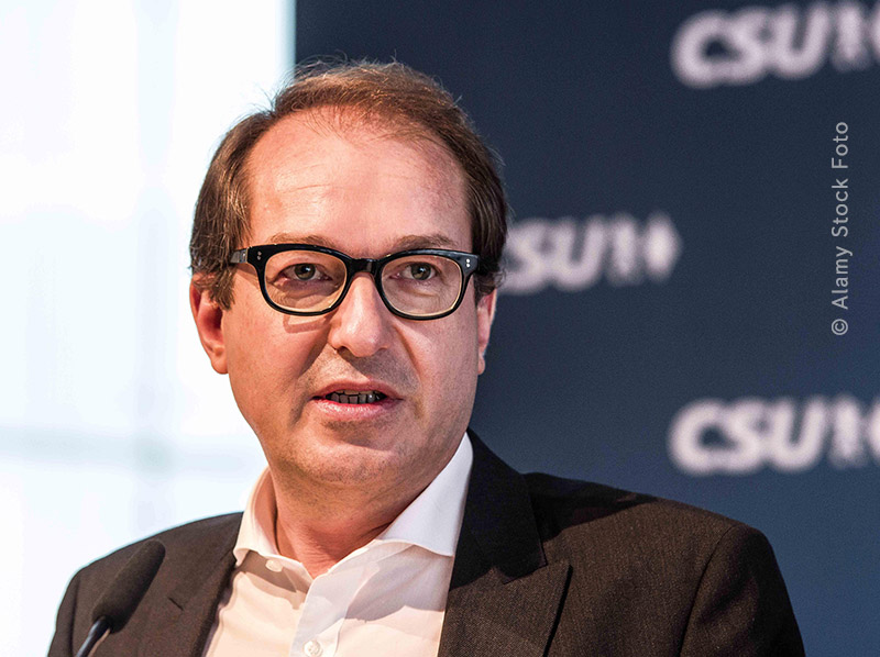Alexander Dobrindt (CSU) spricht bei einer Veranstaltung; Porträt des CSU-Politikers im Anzug mit Brille vor einem Hintergrund mit CSU-Logo.